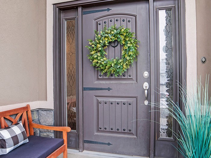 Dark brown door with green wreath and beautiful bench. 